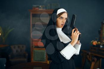 Young nun in a cassock holds a gun, vicious desires. Corrupt sister in the monastery, religion and faith, sinful religious people, attractive sinner