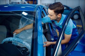 Worker in uniform puts the seat cover, car service station. Automobile checking and inspection, professional diagnostics and repair