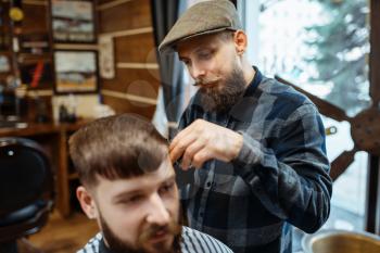 Barber holds comb and cuts the client 's hair. Professional barbershop is a trendy occupation. Male hairdresser and customer in retro style salon