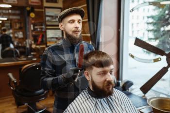 Barber holds comb and cuts the client 's hair. Professional barbershop is a trendy occupation. Male hairdresser and customer in retro style hair salon