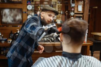 Barber makes a haircut to a client. Professional barbershop is a trendy occupation. Male hairdresser and customer in retro style hair salon