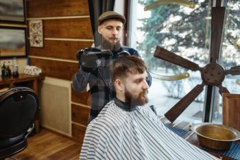 Barber with comb and hairdryer makes a hairstyle to a client. Professional barbershop is a trendy occupation. Male hairdresser and customer in retro style hair salon