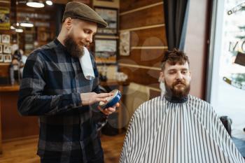 Barber in hat and bearded customer. Professional barbershop is a trendy occupation. Male hairdresser and client in hair salon, stylish hairstyle