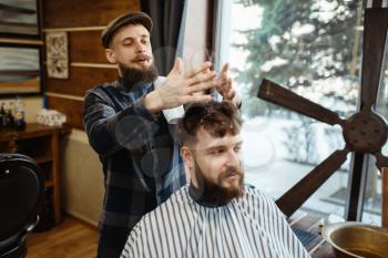 Barber in hat and bearded customer. Professional barbershop is a trendy occupation. Male hairdresser and client in hair salon, stylish hairstyle