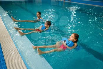 Children swimming group, workout with dumbbells in the pool. Kids learns to swim in the water, sport training, fitness exercise
