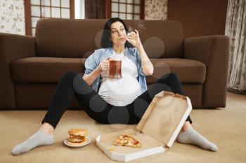 Pregnant woman with belly smoking and drinks beer at home. Pregnancy and bad habits, unhealthy lifestyle in prenatal period. Ugly expectant mom, health damage, alcoholism
