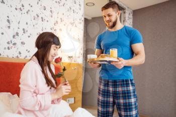 Romantic love couple, breakfast in bed at home, good morning. Harmonious relationship in young family. Man and woman resting together in their house, carefree weekend