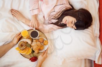 Romantic love couple, breakfast and rose in bed at home, good morning, caring husband. Harmonious relationship in young family. Man and woman resting together in their house, carefree