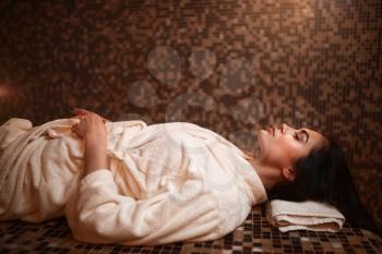 Woman lying on a hot stone, turkish hamam, sauna, side view. Healthcare, skincare and body care