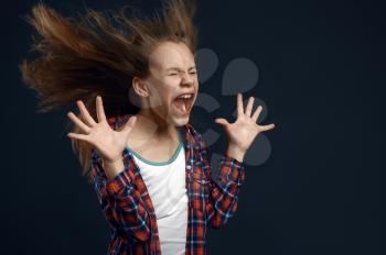 Little girl against powerful airflow in studio, developing hairstyle effect. Children and wind, kid isolated on dark background, child emotion