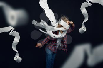 Little girl against powerful airflow, developing hair, windy effect, rolls of toilet paper flying in studio. Children and wind, kid isolated on dark background, child emotion