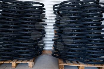 Stacks of new bicycle wheels on a pallet, nobody. Bike parts store on factory, tires in hangar, rows of cycle rims and tyres