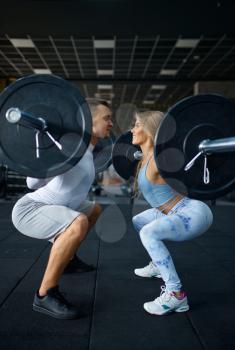Slim couple doing exercise with barbells, training in gym. Athletic man and woman on workout in sport club, active healthy lifestyle, physical wellness