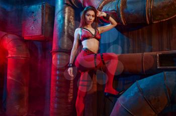 Sexy woman poses in red bdsm stockings, abandoned factory interior on background. Young girl in erotic underwear, sex fetish, sexual fantasy