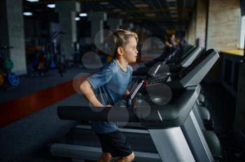 Boy doing exercise on treadmill in gym, running machine. Schoolboy on training in sport club, health care and healthy lifestyle