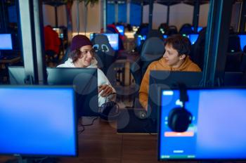 Two gamers play on computers in gaming club. Virtual entertainment, e-sport tournament, cybersport lifestyle. Male person leisures in internet cafe
