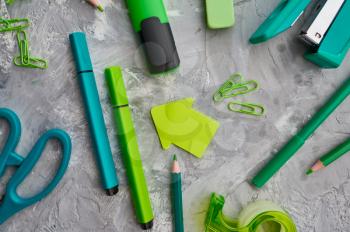 Office stationery supplies in green tones, marble background. School or education accessories, writing and drawing tools, pencils and rubbers, ruler and paper clips