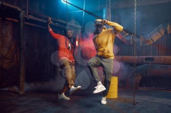 Two stylish rappers, breakdancing in studio with cool underground decoration