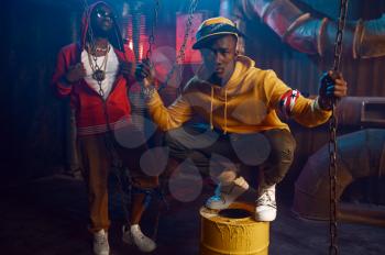 Two stylish rappers dancing in studio with cool underground decoration. Hip-hop performers