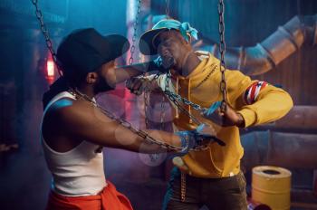 Two rappers posing, performing in studio with cool underground decoration. Hip-hop performers, trendy rap singers, break-dancers