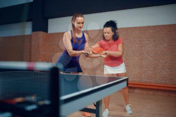 Woman with female instructor, ping pong training, table tennis players. Friends playing table-tennis indoors, sport game with ball, active healthy lifestyle