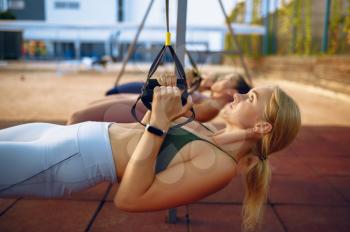 Women's group, exercise with ropes on sports ground, front view, outdoors fitness training. Slim female athletes in sportswear, team fit workout, teamwork
