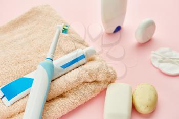 Oral care products, toothbrush, toothpaste and dental floss on towel, pink background, nobody. Morning healthcare procedures concept
