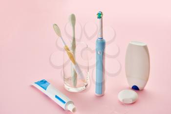 Oral care products, toothbrush, toothpaste and dental floss, pink background, nobody. Morning healthcare procedures concept