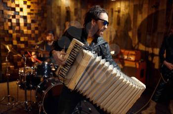 Two brutal musicians with accordion and electric guitar, music performing on stage. Rock band performance, concert repetition in garage, man with musical instrument, live sound performer