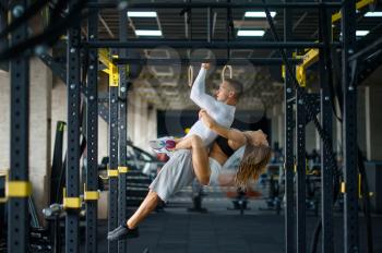 Sportive love couple hugs on horizontal bar, training in gym. Athletic man and woman on workout in sport club, active healthy lifestyle, physical wellness