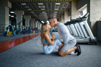 Love couple kissing, fitness training in gym. Athletic man and woman on workout in sport club, active healthy lifestyle, physical wellness