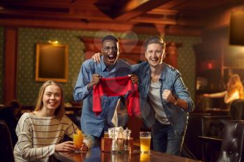 Football fans with red scarf watching game translation, friends in bar. Group of people relax in pub, night lifestyle, friendship, sport celebration