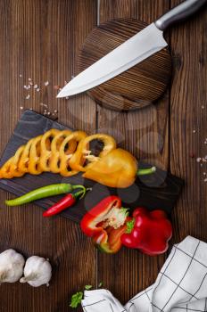 Fresh cutted pepper on board, top view, wooden background. Organic vegetarian food, grocery assortment, natural products, healthy lifestyle concept