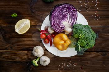 Fresh vegetables in plates, top view, on wooden background. Organic vegetarian food, grocery assortment, natural products, healthy lifestyle concept