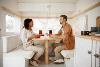 Love couple having breakfast in rv, camping in a trailer. Man and woman travels on van, romantic vacations on motorhome, campers leisures in camping-car