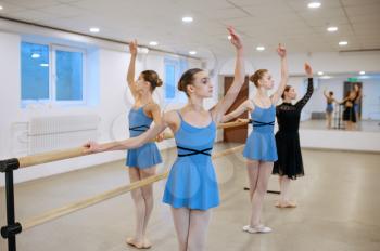 Master and young ballerinas exercise at the barre in class. Ballet school, female dancers on choreography lesson, girls practicing grace dance