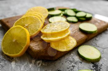 Fresh cutted lemon and cucumber on grunge abstract background. Organic vegetarian food, grocery assortment, natural eco products, healthy lifestyle concept