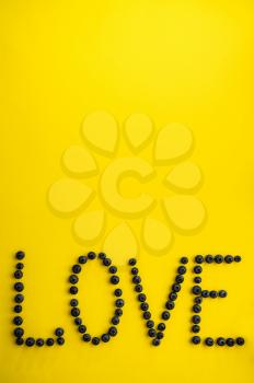 Berries love word isolated on yellow background, top view. Organic vegetarian food, grocery assortment, natural eco products, healthy lifestyle concept