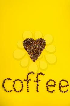 Coffee bean heart and word isolated on yellow background, top view. Organic vegetarian food, grocery assortment, natural eco products, healthy lifestyle concept