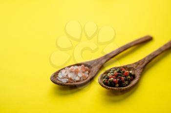Fragrant spices in a spoon and red pepper isolated on yellow background, top view. Organic vegetarian food, grocery assortment, natural eco products, healthy lifestyle concept