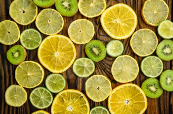 Fresh kiwi and lemon slices on wooden background, top view. Organic vegetarian food, grocery assortment, natural eco products, healthy lifestyle concept