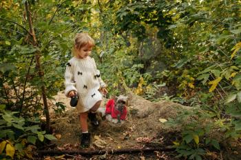 Kid with funny doggy walking in the forest, best friends. Female child with puppy outdoors. Little girl and her pet having an interesting adventure outside, happy childhood
