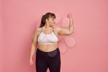 Overweight woman shows muscles, pink background, body positive. Obesity fighting, striving for a healthy lifestyle