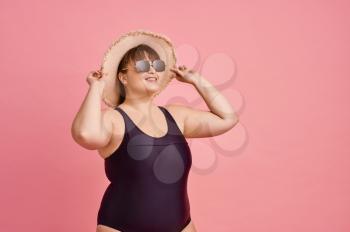 Overweight woman in swimsuit prepares for summer vacations, body positive, pink background. Obesity fighting, cheerful female person without complexes, striving for a healthy lifestyle
