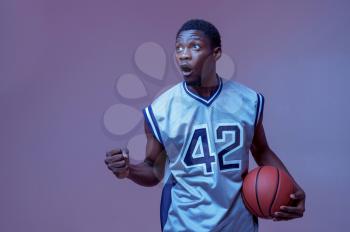 Confident basketball player poses with ball in studio, neon background. Professional male baller in sportswear playing sport game, tall sportsman