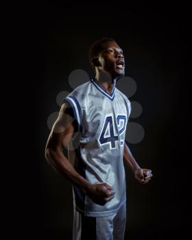 Aggressive basketball player poses in studio, black background. Professional male baller in sportswear playing sport game, tall sportsman