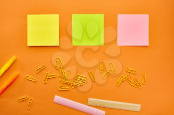 Paper clips, notepad and ruler closeup on orange background. Office stationery supplies, school or education accessories, writing and drawing tools