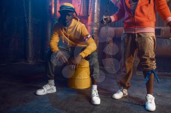 Two stylish rappers poses in studio with cool underground decoration. Hip-hop performers, trendy rap singers, break-dancers