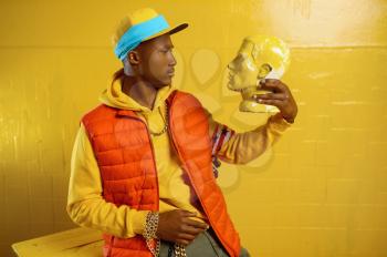 Young stylish rapper poses in studio with yellow tones. Hip-hop performer, rap singer, break-dance performing, entertainment lifestyle