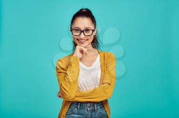 Smiling woman in glasses, blue background, positive emotion. Face expression, female person looking on camera in studio, emotional concept, feelings